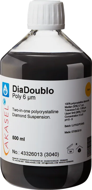 Akasel DiaDoublo Poly 6 µm: En 500 ml plastflaska med vit skruvkork, innehållande en svart polykrystallin diamantsuspension. Etiketten visar produktnamnet “DiaDoublo Poly 6 µm” tillsammans med beskrivningen “Two-in-one polycrystalline Diamond Suspension.” Ytterligare detaljer inkluderar: “100% polycrystalline diamonds,” “Median (50%) 5.7 µm,” “Tolerance 5.42 – 5.98 µm,” “Upper limit (99%) 7.9 µm,” och en koncentration på “10 ct/l.” Symboler på etiketten anger lagringsförhållanden och hållbarhet.